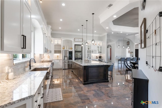 kitchen featuring arched walkways, marble finish floor, ornamental molding, and white cabinetry