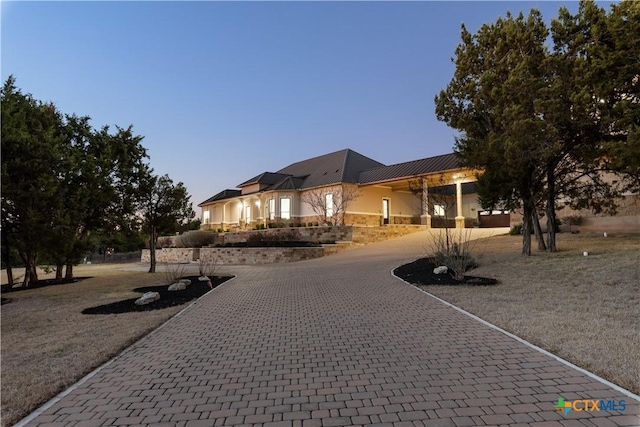 view of front facade featuring stone siding and curved driveway