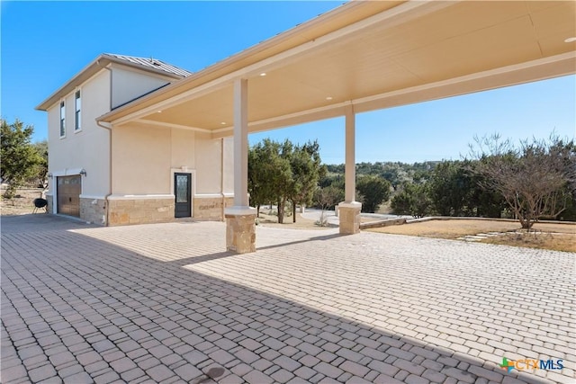 view of patio / terrace featuring a garage and decorative driveway