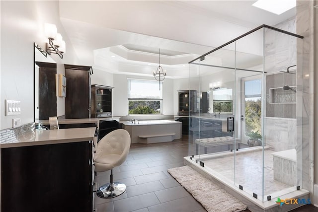 full bathroom with ornamental molding, a freestanding tub, a stall shower, and a raised ceiling