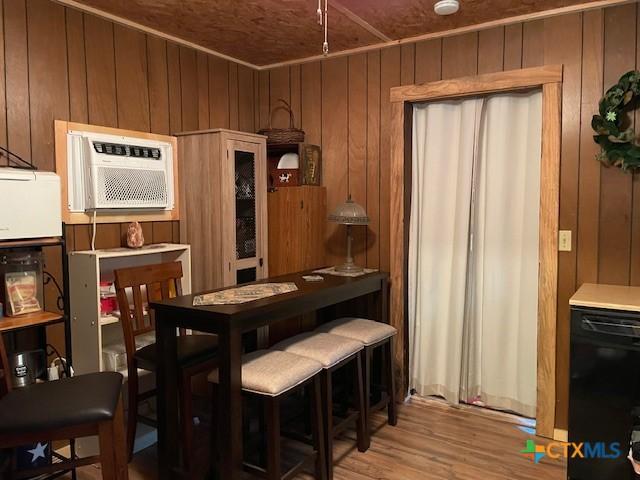 dining room with light hardwood / wood-style floors, wooden ceiling, wooden walls, and a wall mounted AC