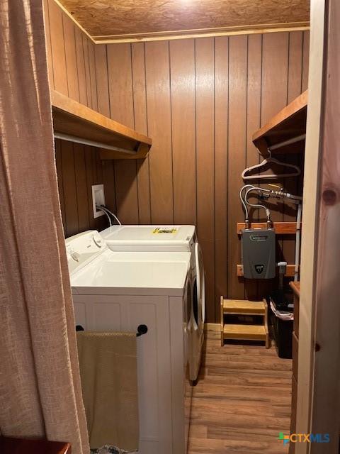 laundry room with light hardwood / wood-style floors, washer and dryer, wood walls, and wood ceiling