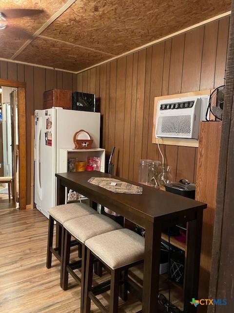 dining area with wood walls, light hardwood / wood-style flooring, wood ceiling, and a wall mounted air conditioner