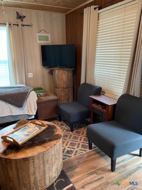 sitting room with wood ceiling, wood walls, and light hardwood / wood-style floors