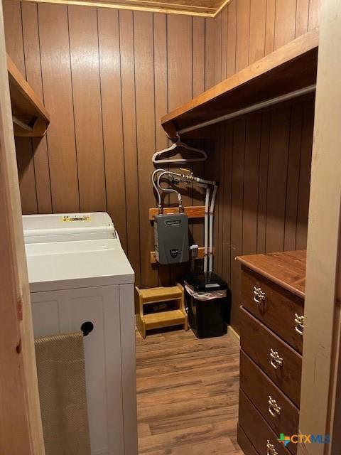 laundry room with wooden walls, washer / clothes dryer, and light hardwood / wood-style flooring