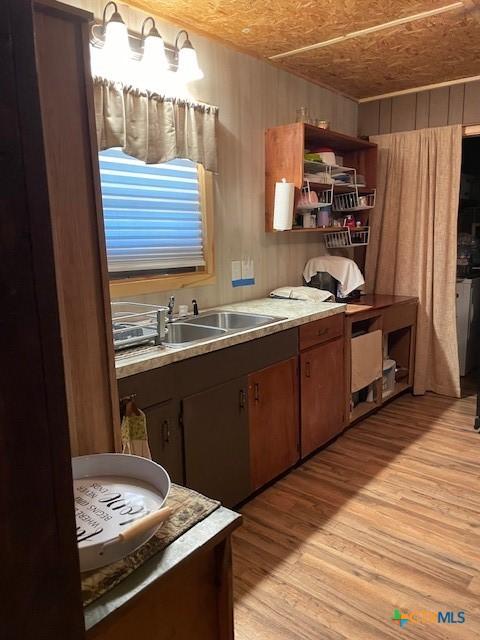 kitchen with wood walls, sink, and light hardwood / wood-style floors