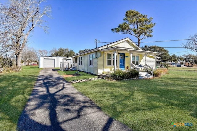 view of front of house featuring an outdoor structure, driveway, a porch, and a front yard
