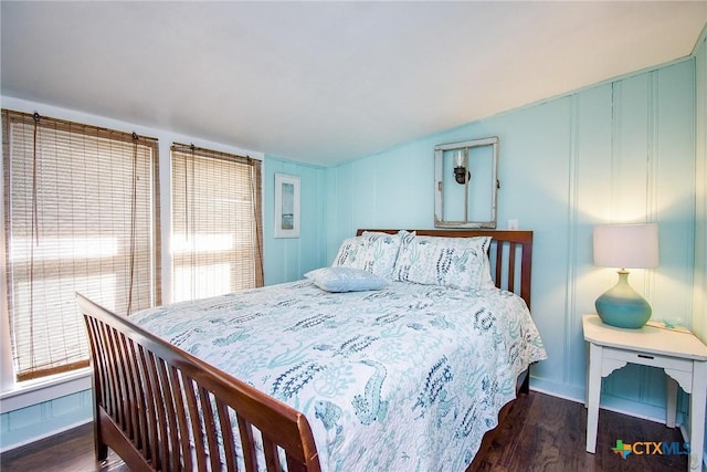 bedroom with wood finished floors and a decorative wall