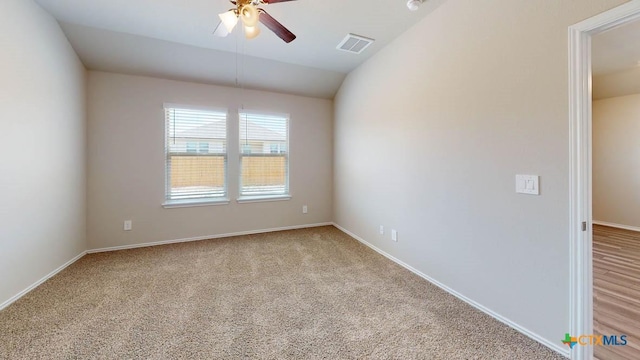 empty room with light carpet, baseboards, visible vents, ceiling fan, and vaulted ceiling