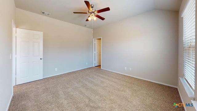 empty room featuring carpet floors, visible vents, baseboards, vaulted ceiling, and a ceiling fan