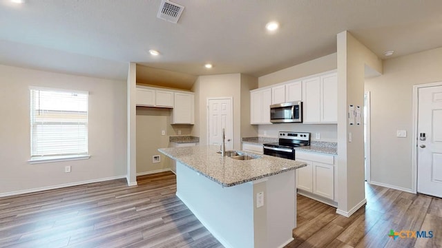 kitchen with stainless steel appliances, a sink, visible vents, white cabinets, and an island with sink