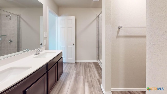 full bath featuring a sink, double vanity, wood finished floors, and a shower stall