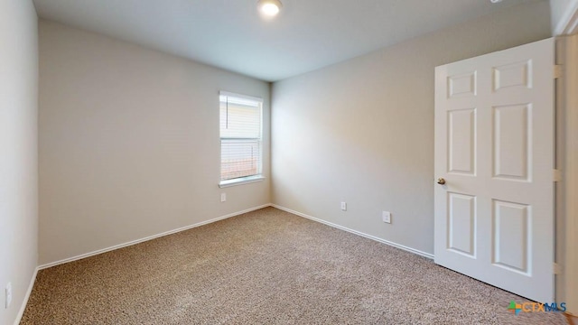 carpeted empty room featuring baseboards