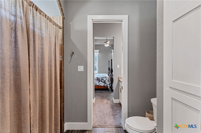 bathroom featuring toilet, hardwood / wood-style flooring, and ceiling fan