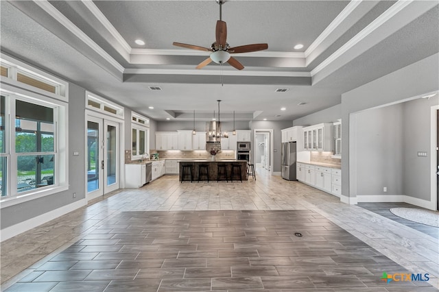 unfurnished living room featuring crown molding, a textured ceiling, a raised ceiling, sink, and ceiling fan