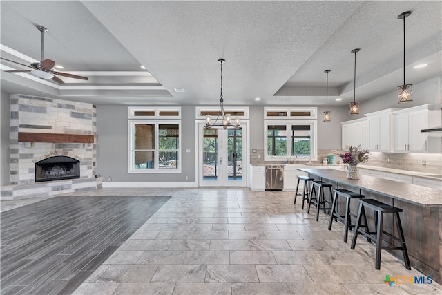 kitchen featuring a breakfast bar area, white cabinetry, a raised ceiling, and a healthy amount of sunlight