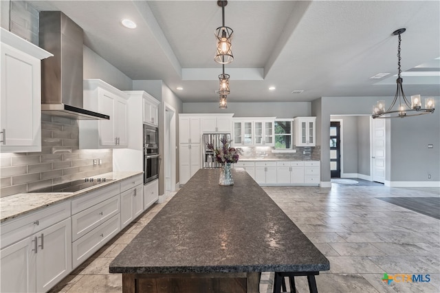 kitchen with stainless steel appliances, white cabinetry, hanging light fixtures, a spacious island, and wall chimney range hood