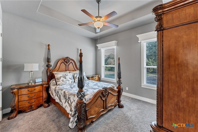 carpeted bedroom featuring ceiling fan and a tray ceiling