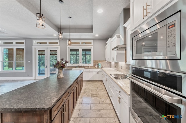 kitchen featuring french doors, backsplash, appliances with stainless steel finishes, white cabinets, and a center island