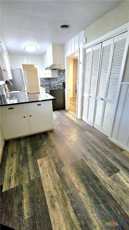 kitchen featuring dark countertops, white cabinets, visible vents, and wood finished floors