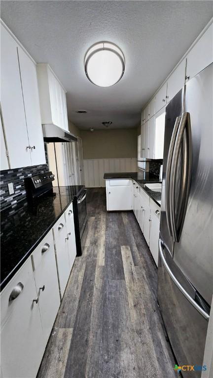 kitchen with electric range, white cabinets, dark countertops, dark wood-style flooring, and freestanding refrigerator