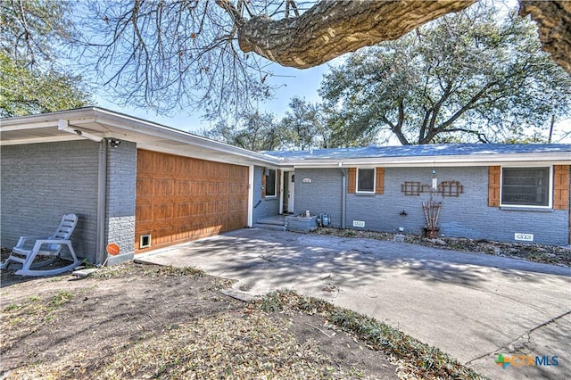 back of property featuring crawl space, a garage, driveway, and brick siding