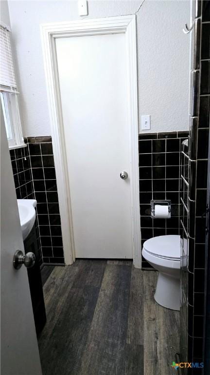 bathroom featuring toilet, tile walls, and wood finished floors