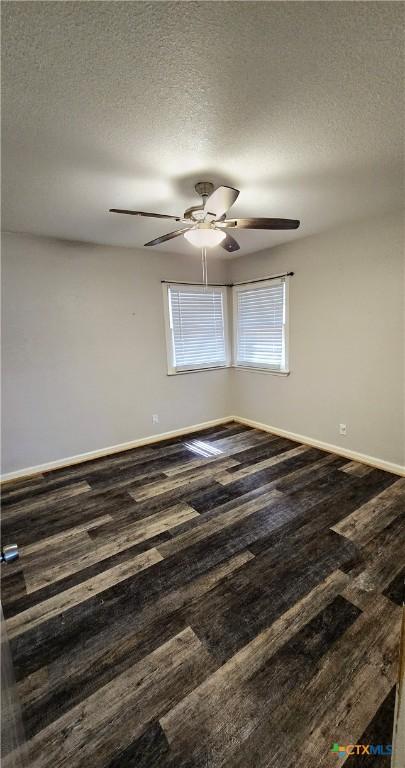 spare room with a textured ceiling, ceiling fan, wood finished floors, and baseboards