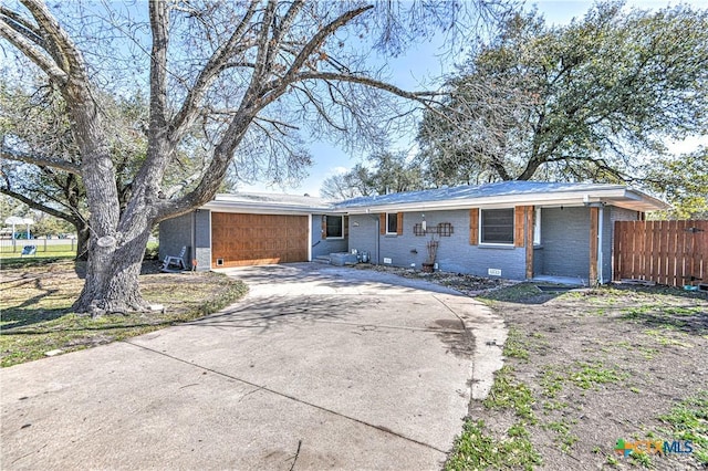 ranch-style house with concrete driveway, fence, brick siding, and crawl space