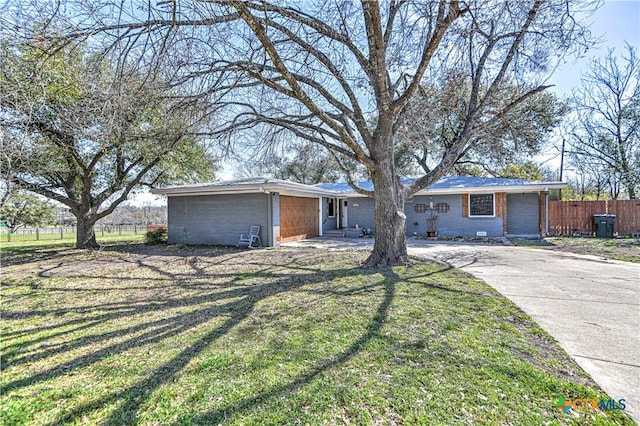 view of front facade featuring a front yard, fence, brick siding, and driveway