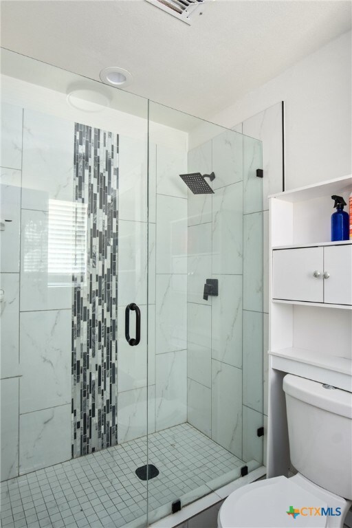 bathroom featuring walk in shower and toilet