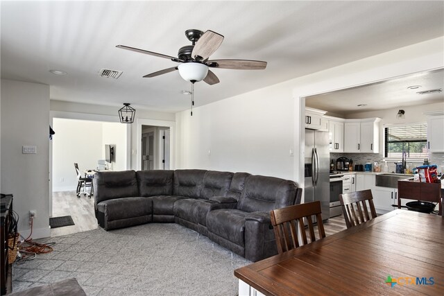 living room featuring light hardwood / wood-style floors, ceiling fan, and sink