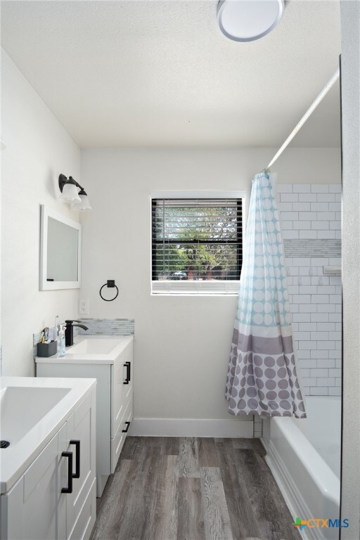 bathroom with wood-type flooring, vanity, and shower / tub combo