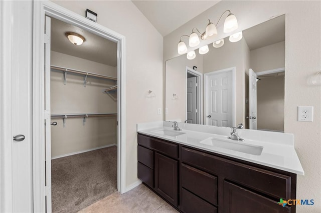 full bath featuring tile patterned floors, double vanity, a sink, and a walk in closet