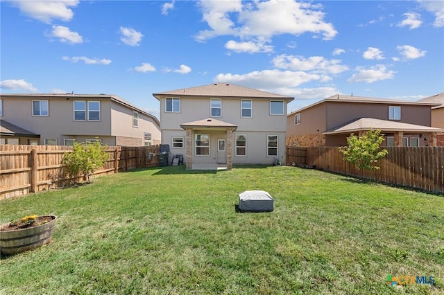 rear view of property with a fenced backyard and a lawn