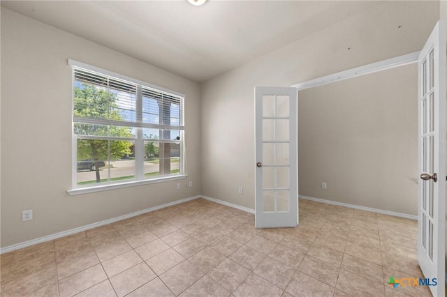 spare room featuring french doors, light tile patterned floors, baseboards, and lofted ceiling