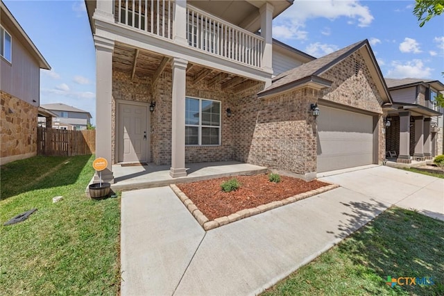 view of front of property with a front yard, fence, concrete driveway, brick siding, and a balcony
