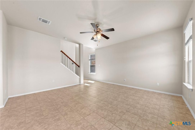 unfurnished room with visible vents, baseboards, a ceiling fan, stairway, and light tile patterned flooring
