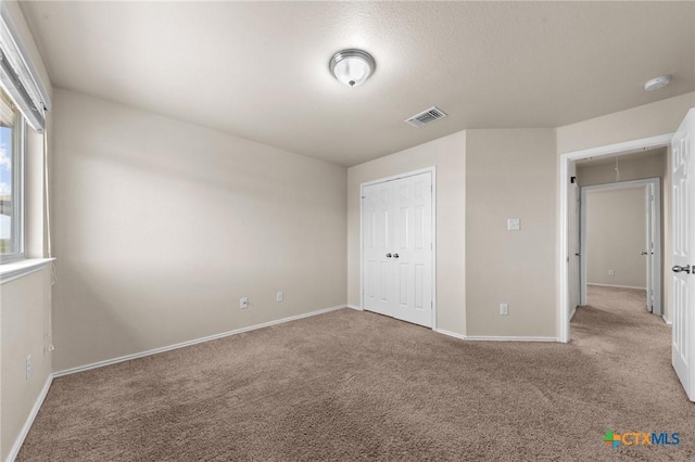 unfurnished bedroom featuring visible vents, baseboards, and carpet flooring