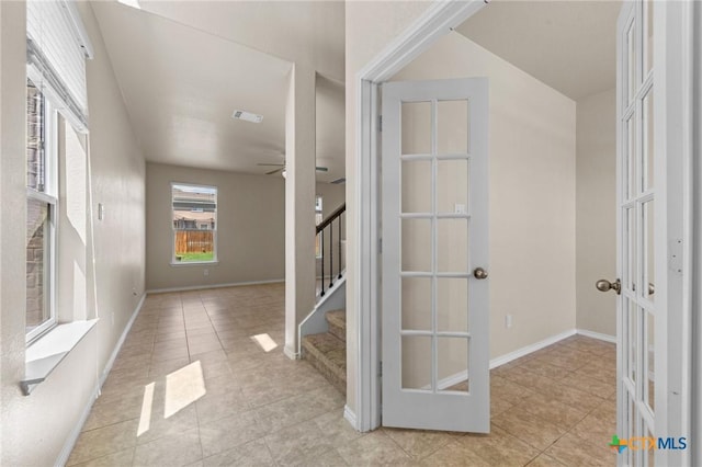 interior space with light tile patterned floors, baseboards, visible vents, stairs, and french doors