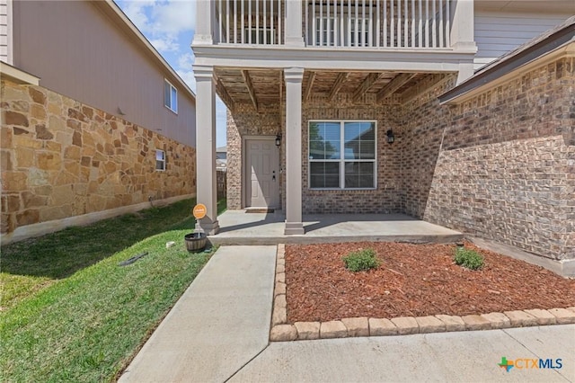 property entrance featuring brick siding and a balcony