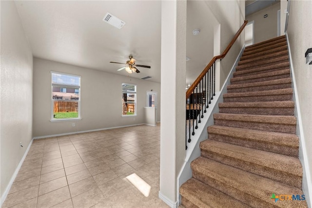 stairs with tile patterned flooring, visible vents, baseboards, and a ceiling fan
