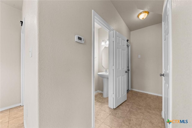 hallway with light tile patterned floors and baseboards