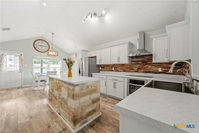 1110 Twin Deer Ln, Canyon Lake, TX 78133 - kitchen featuring wall chimney range hood, stainless steel appliances, light wood-style flooring, lofted ceiling, and light countertops