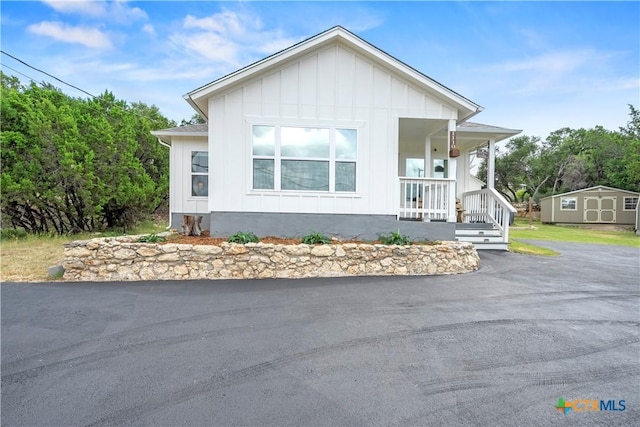 1110 Twin Deer Ln, Canyon Lake, TX 78133 - manufactured / mobile home with board and batten siding, a porch, and a storage shed