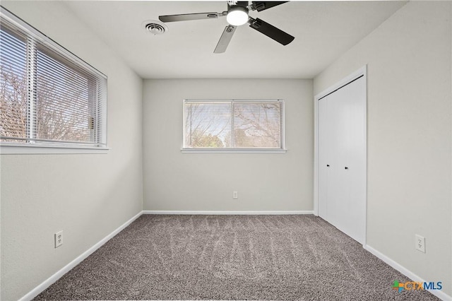 unfurnished bedroom with ceiling fan, multiple windows, a closet, and carpet floors