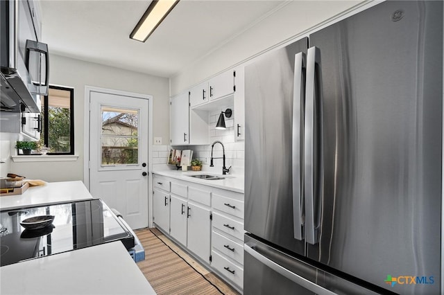 kitchen featuring stainless steel appliances, white cabinetry, sink, and tasteful backsplash