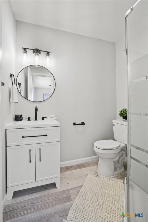 bathroom with walk in shower, toilet, vanity, and wood-type flooring