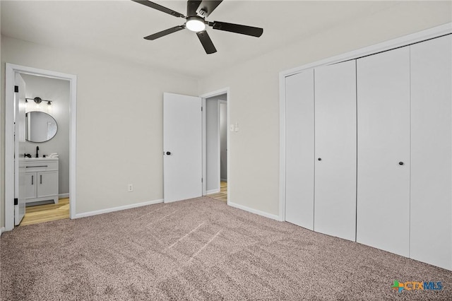 unfurnished bedroom featuring sink, ensuite bathroom, light carpet, ceiling fan, and a closet