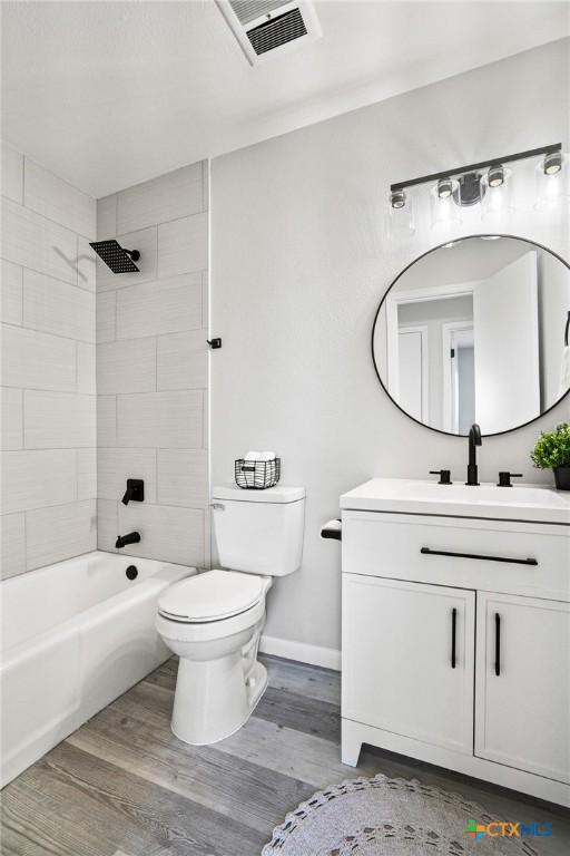 full bathroom with toilet, tiled shower / bath, wood-type flooring, and vanity